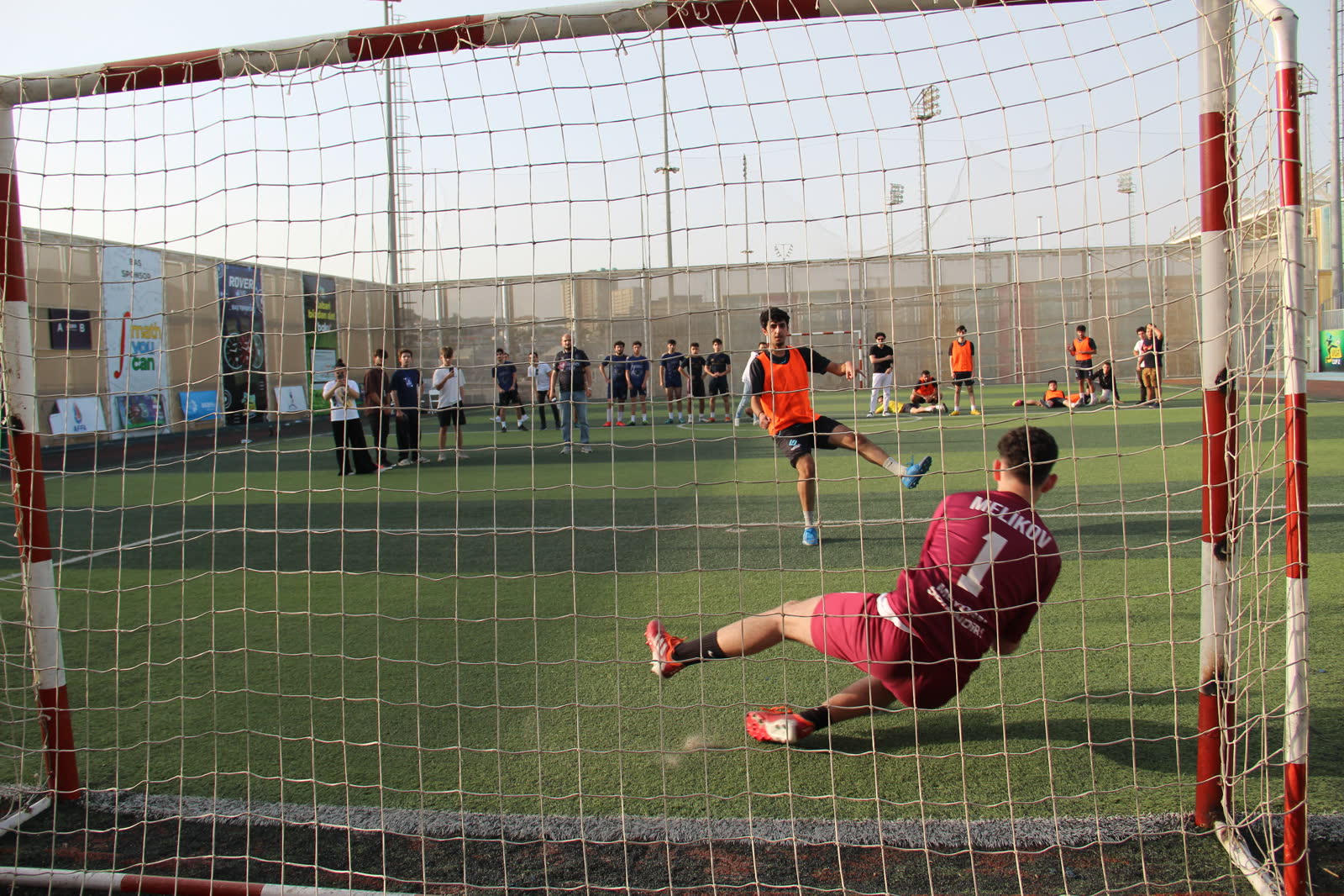 Teyyub diving to save a penalty, seen through the goal net